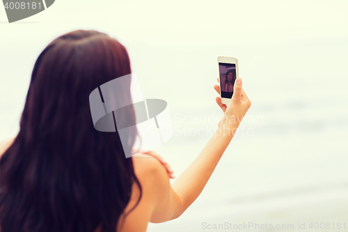 Image of young woman taking selfie with smartphone