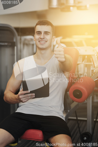 Image of smiling young man with tablet pc computer in gym