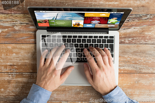 Image of close up of male hands with laptop typing