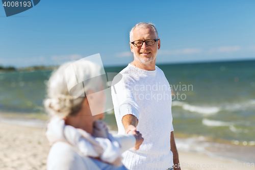 Image of happy senior couple holding hands on summer beach