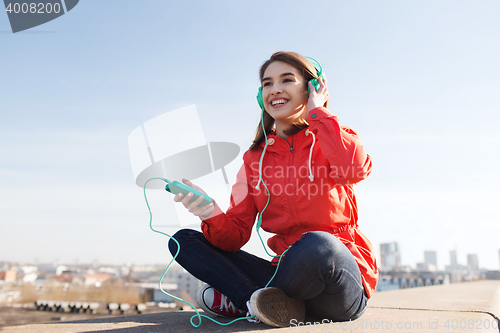 Image of happy young woman with smartphone and headphones