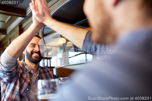 Image of happy male friends making high five at bar or pub