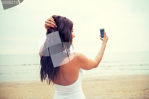 Image of young woman taking selfie with smartphone