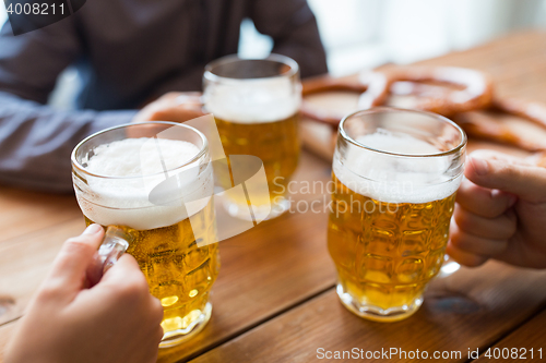 Image of close up of hands with beer mugs at bar or pub