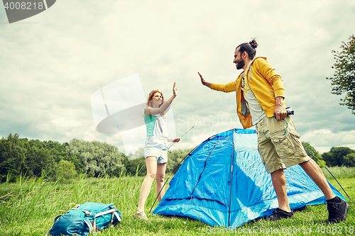 Image of happy couple setting up tent outdoors