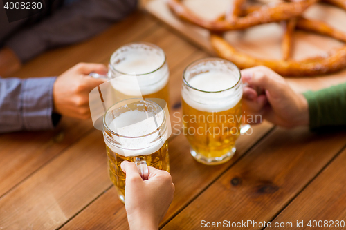 Image of close up of hands with beer mugs at bar or pub