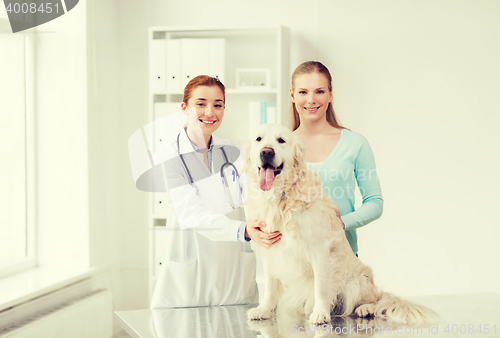 Image of happy woman with dog and doctor at vet clinic