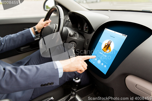 Image of man driving car with music on board computer