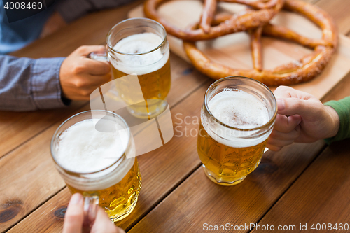 Image of close up of hands with beer mugs at bar or pub