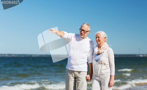 Image of happy senior couple walking on summer beach