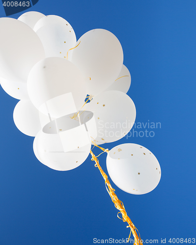 Image of close up of white helium balloons in blue sky