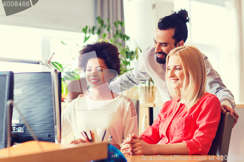Image of happy creative team with computer in office