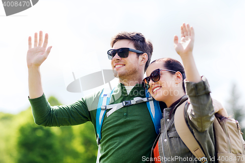 Image of happy couple with backpacks hiking outdoors