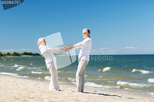 Image of happy senior couple holding hands on summer beach