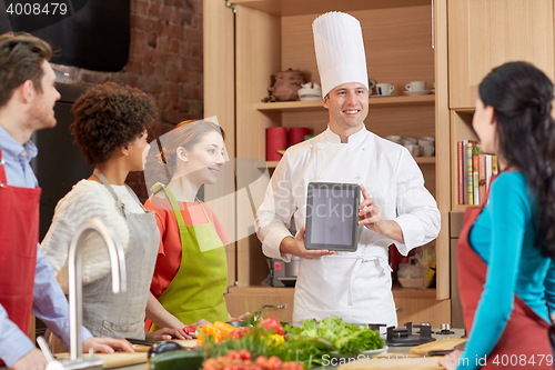 Image of happy friends with tablet pc in kitchen