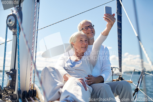Image of seniors with smartphone taking selfie on yacht