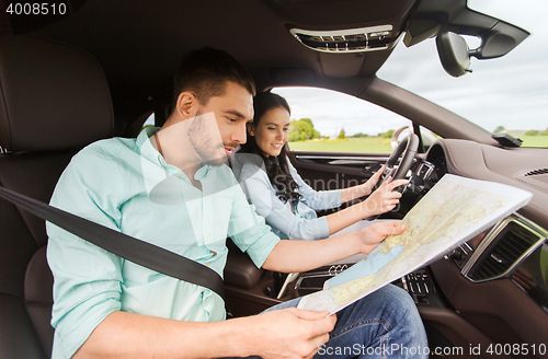 Image of happy man and woman with road map driving in car