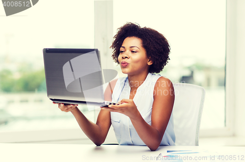 Image of african woman sending kiss to laptop computer