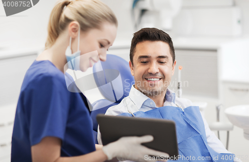 Image of female dentist with tablet pc and male patient