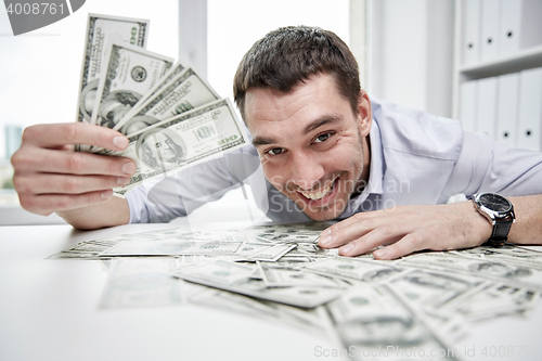 Image of happy businessman with heap of money in office