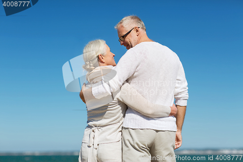 Image of happy senior couple hugging on summer beach