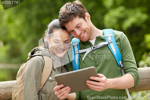 Image of happy couple with backpacks and tablet pc outdoors