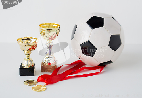 Image of close up of football ball, golden cups and medals