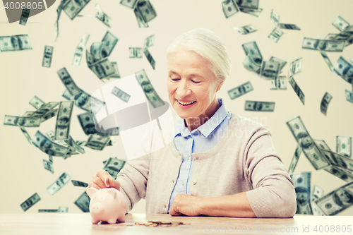 Image of senior woman putting money to piggy bank at home