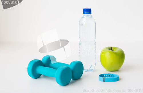 Image of dumbbells, fitness tracker, apple and bottle