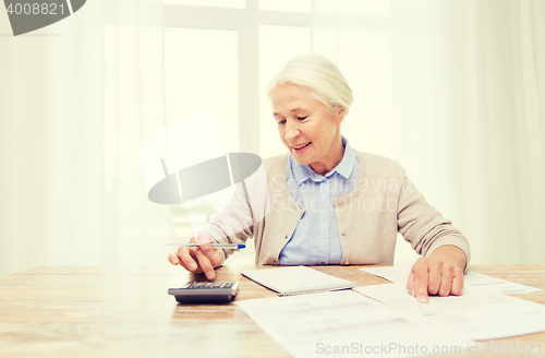 Image of senior woman with papers and calculator at home