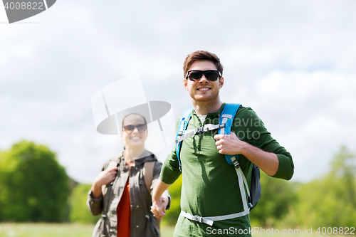 Image of happy couple with backpacks hiking outdoors