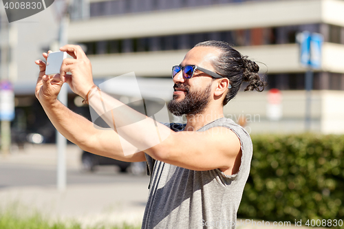 Image of man taking video or selfie by smartphone in city