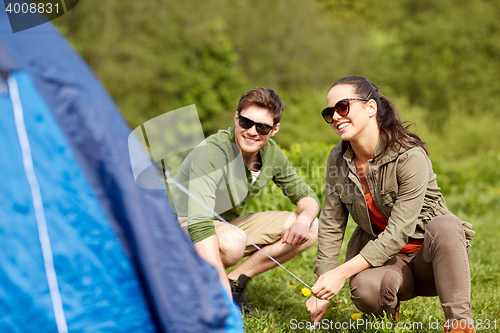 Image of happy couple setting up tent outdoors