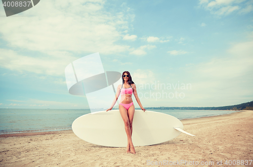 Image of smiling young woman with surfboard on beach