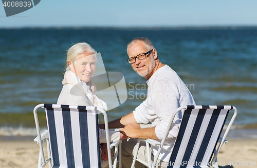 Image of senior couple sitting on chairs at summer beach