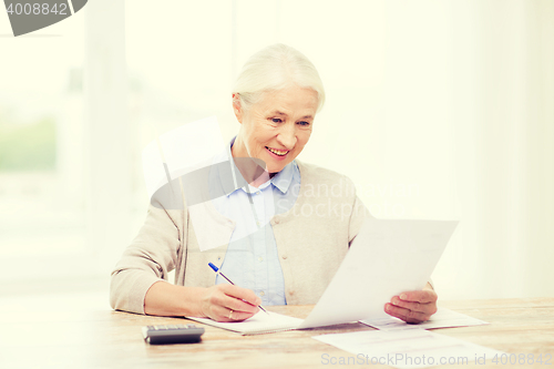 Image of senior woman with papers and calculator at home