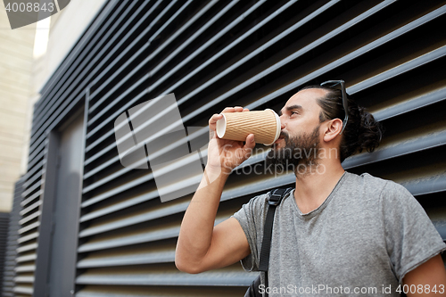 Image of man drinking coffee from paper cup on street