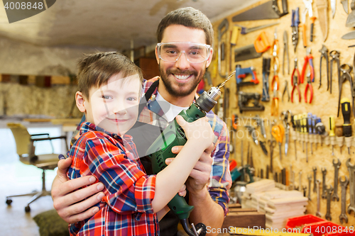Image of father and son with drill working at workshop