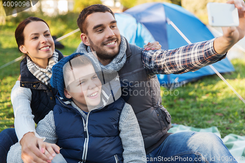 Image of family with smartphone taking selfie at campsite