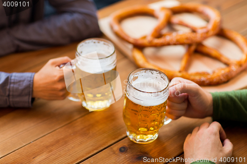 Image of close up of hands with beer mugs at bar or pub