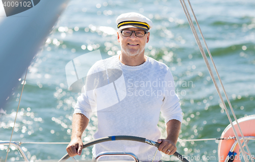 Image of senior man at helm on boat or yacht sailing in sea