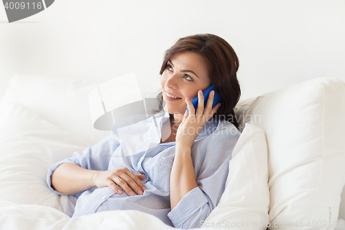 Image of happy pregnant woman calling on smartphone at home