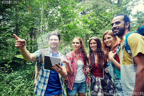 Image of happy friends with backpacks and tablet pc hiking
