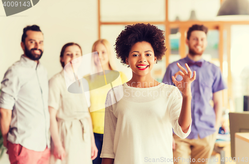 Image of happy woman showing ok over creative office team