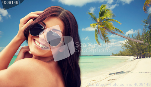 Image of smiling young woman with sunglasses on beach