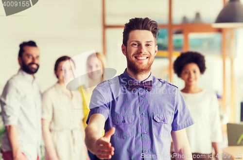 Image of happy man making handshake over office team