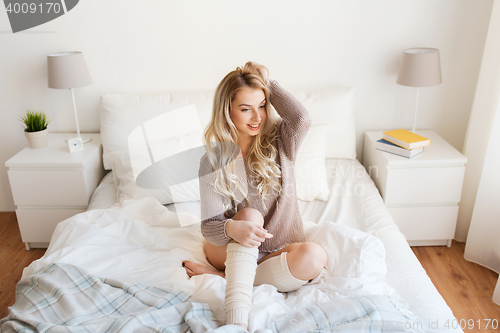 Image of happy young woman posing in bed at home