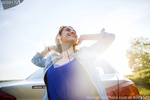 Image of happy teenage girl or young woman near car