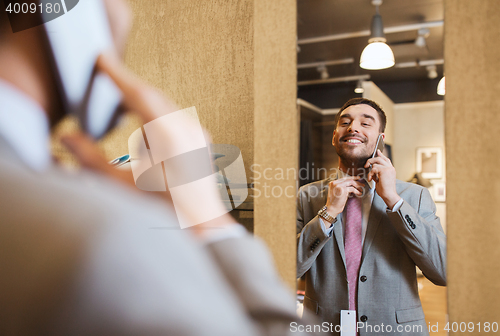 Image of man calling on smartphone at clothing store mirror