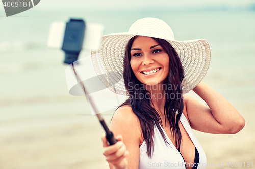 Image of smiling young woman taking selfie with smartphone